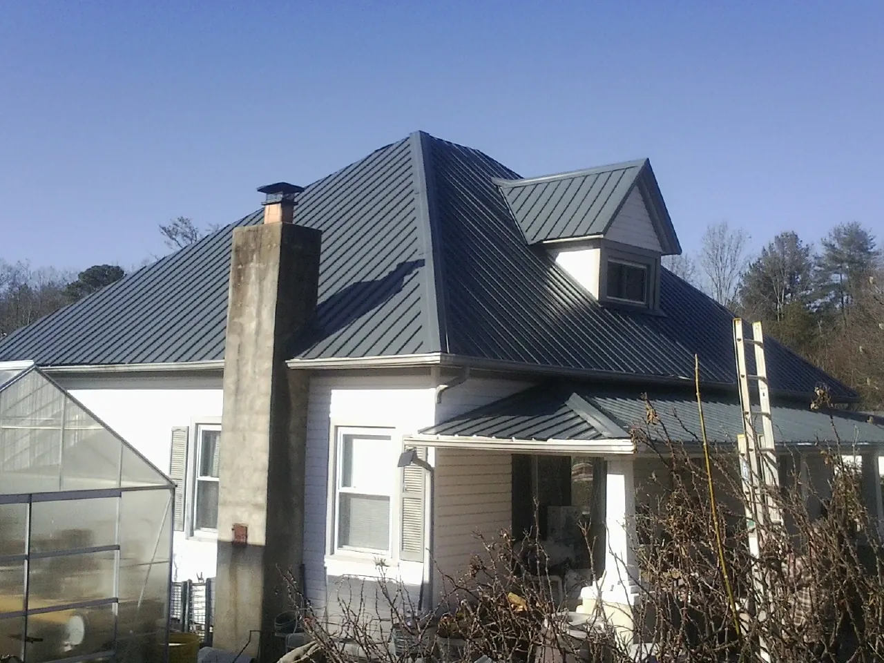 Dark blue standing seam metal roof on a white farmhouse with dormer — Slate & Tile Roof Repair by Roofing Brothers in Princeton Junction