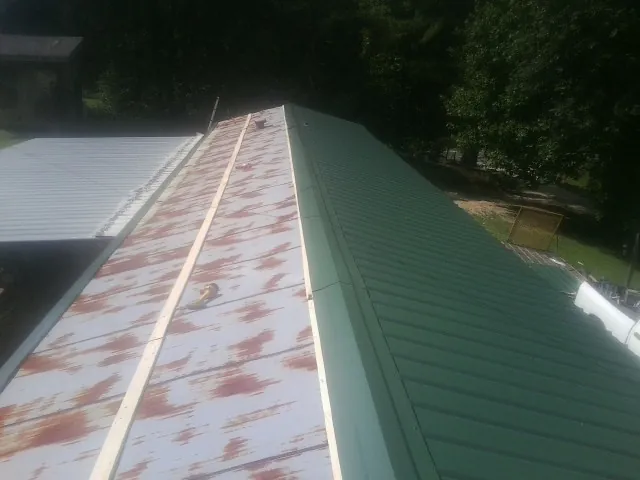 Old rusted panels beside newly installed green metal roofing — Wind Damage Roof Repair by Roofing Brothers in Princeton Junction
