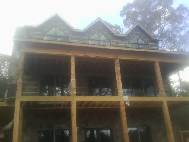 Dormers and porch framing on a large log home under construction — Roof Coating work by our crew in Princeton Junction