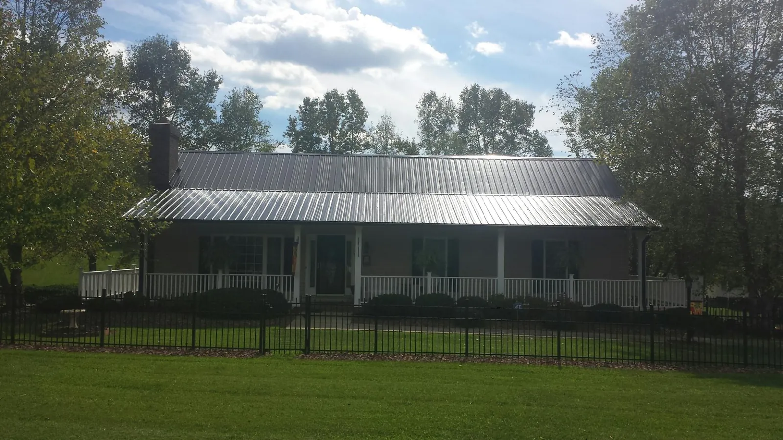 Gray metal roof on a brick ranch with a full width front porch — Gutter Guard Installation work by our crew in Princeton Junction