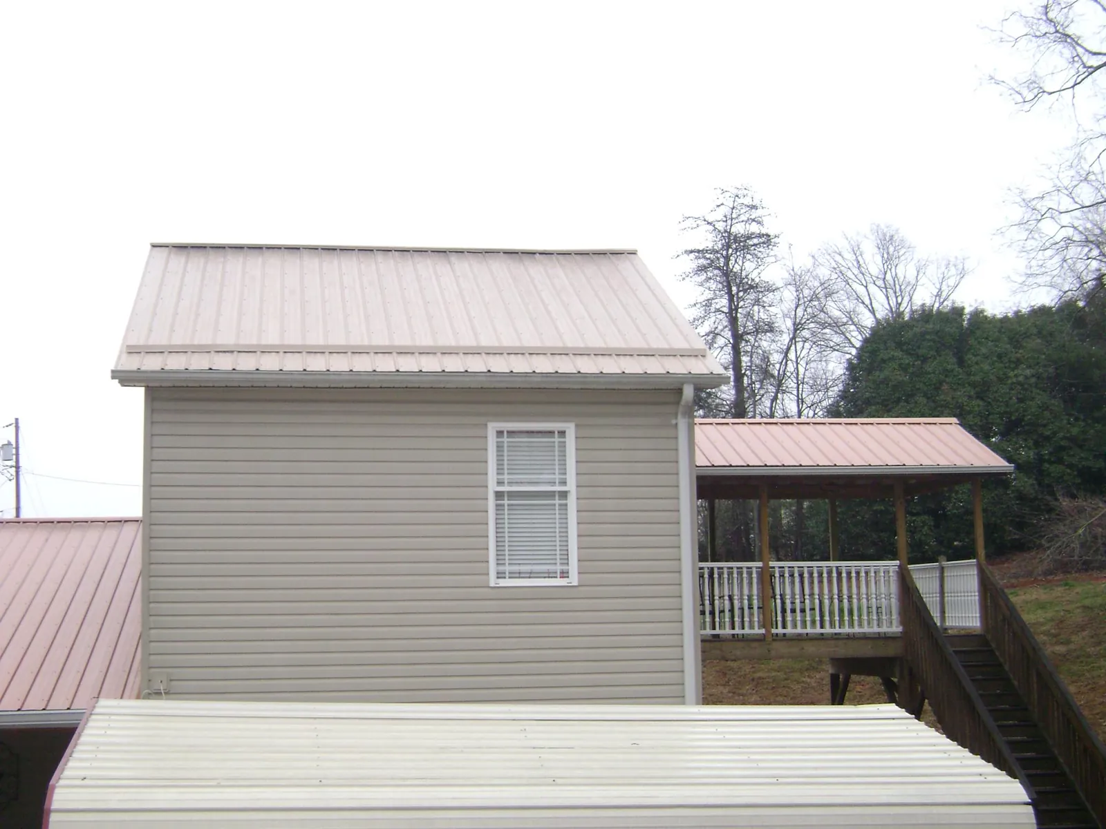 Tan metal roofs on a two story addition and attached porch, from a Roof Replacement job in Princeton Junction