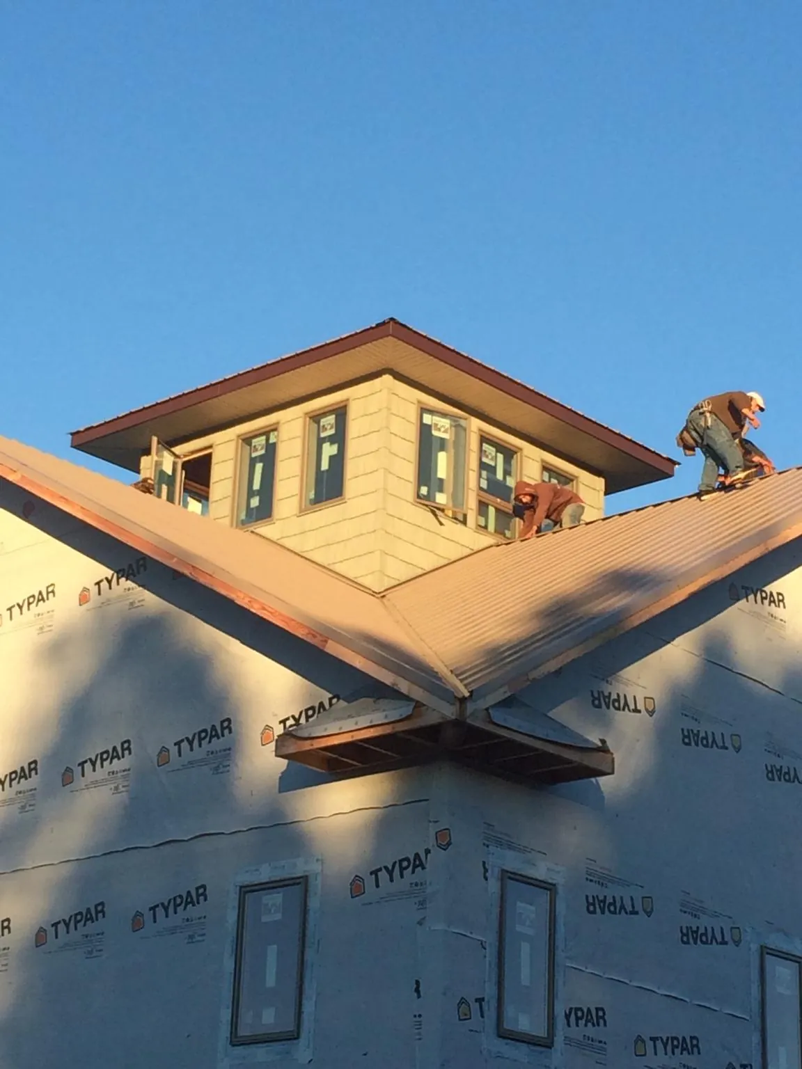 Roofers working around a rooftop cupola on a new metal roof at sunset — Roof Waterproofing in Princeton Junction by Roofing Brothers